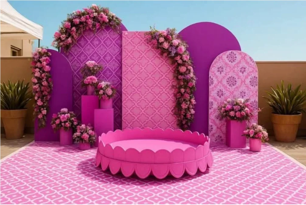 Pink Haldi kund-style seating with floral backdrop, patterned panels and flower arrangements