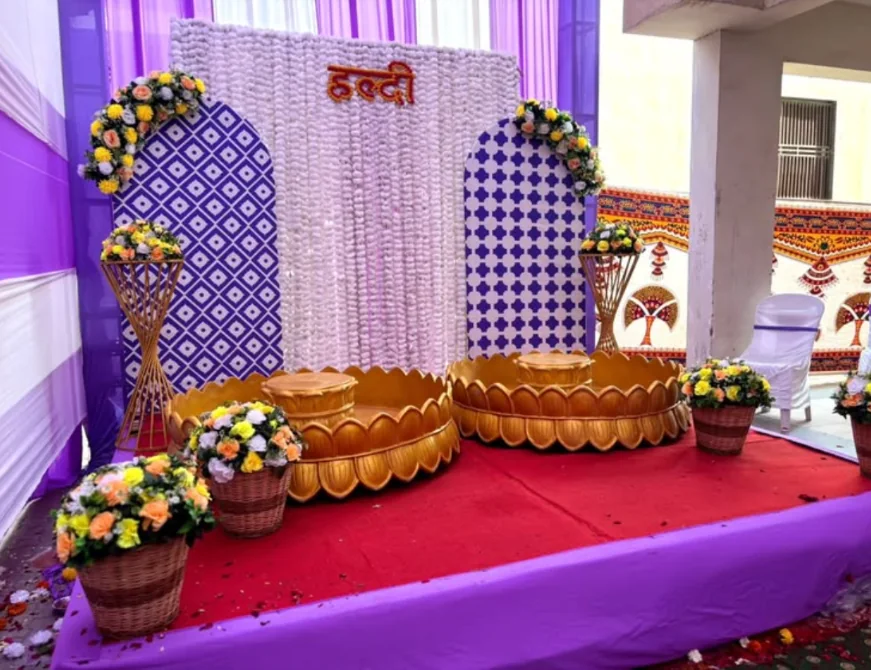 Traditional Haldi setup with gold lotus-style kund seating, floral baskets and a Haldi backdrop